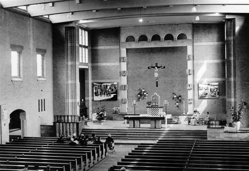 Historische zwart-witfoto van het kerkinterieur met altaar en kerkbanken.