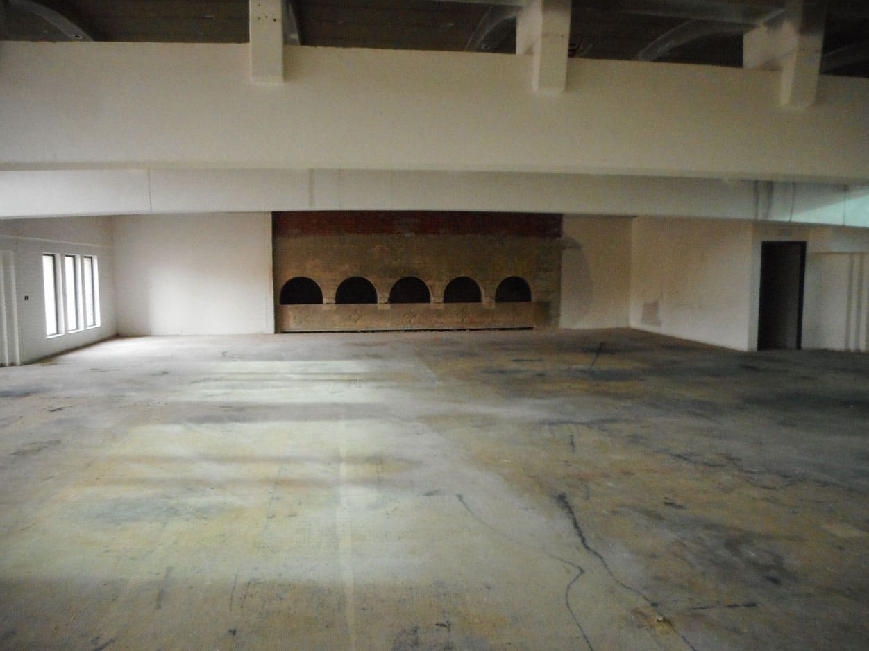 De leeggemaakte ruimte met een betonvloer en een wand met rondbogen.