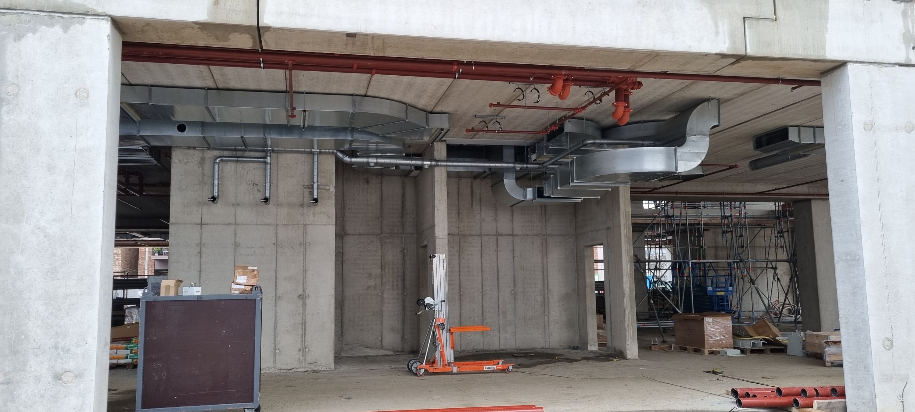 Een kantoorlaag in aanbouw met betonnen wanden, kolommen en installatiekanalen.
