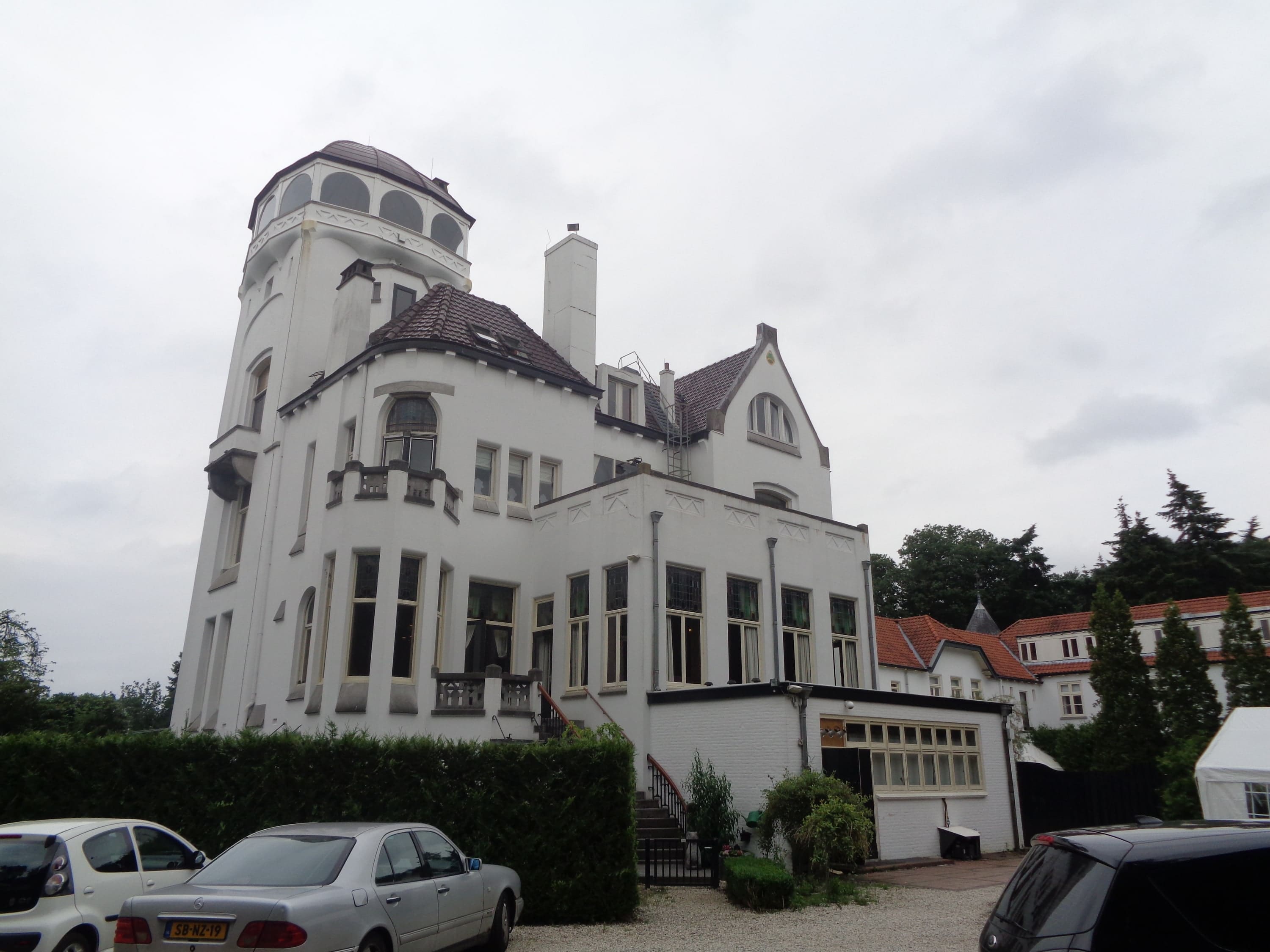 Het witte jachtslot met de hoge toren, gezien vanaf het parkeerterrein.