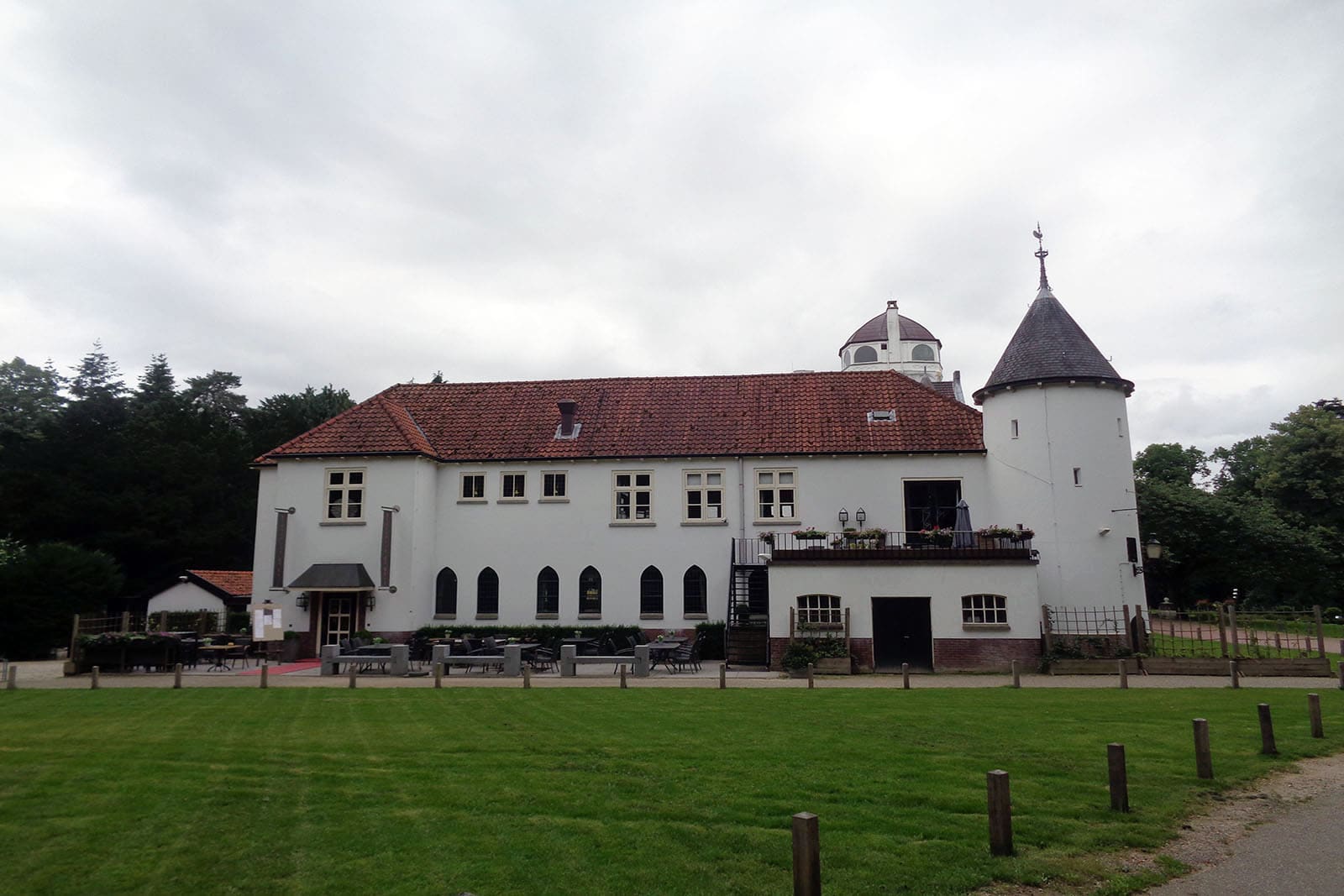 De lange witte zijvleugel van het jachtslot met rood pannendak en een ronde toren.